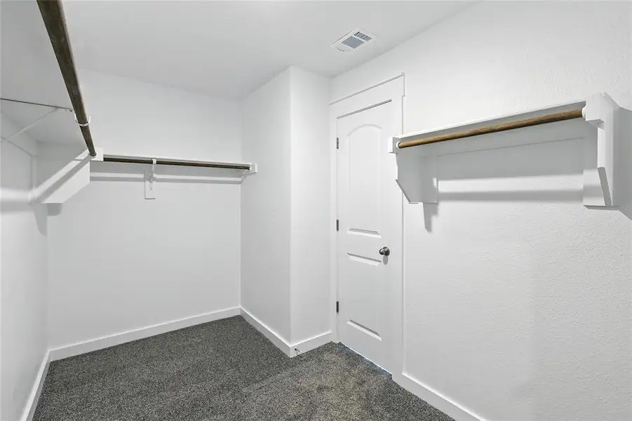 Walk in closet featuring dark carpet Walk in closet featuring dark carpet