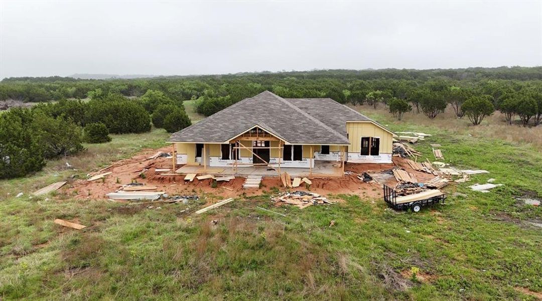 View of front of home featuring a view of trees and roof with shingles
