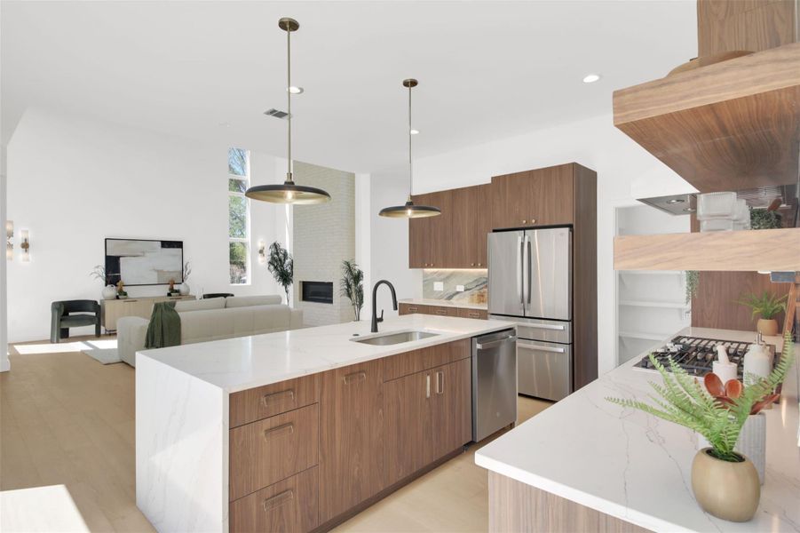 Kitchen featuring light stone counters, a center island with sink, stainless steel appliances, light wood-type flooring, and wood finish cabinets