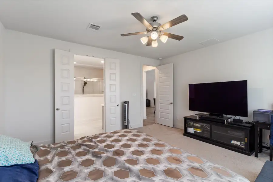 Bedroom featuring a ceiling fan, light carpet, and ensuite bathroom