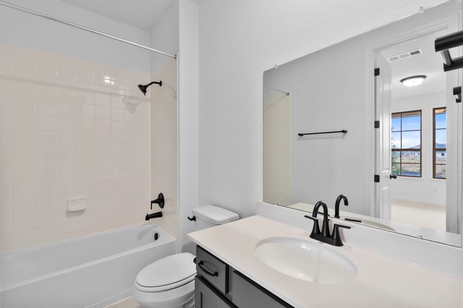 Stylish secondary bath featuring the AW Collection Rosemary with sage green cabinetry and light countertops with matte black fixtures and a shower/tub combo.