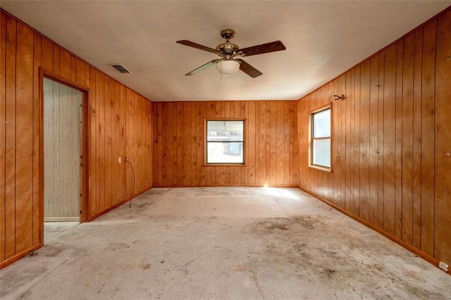 Unfurnished room featuring wood walls and ceiling fan