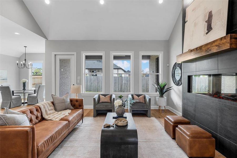 Living room featuring lofted ceiling, a chandelier, recessed lighting, and light wood-style flooring Living room featuring lofted ceiling, a chandelier, recessed lighting, and light wood-style flooring