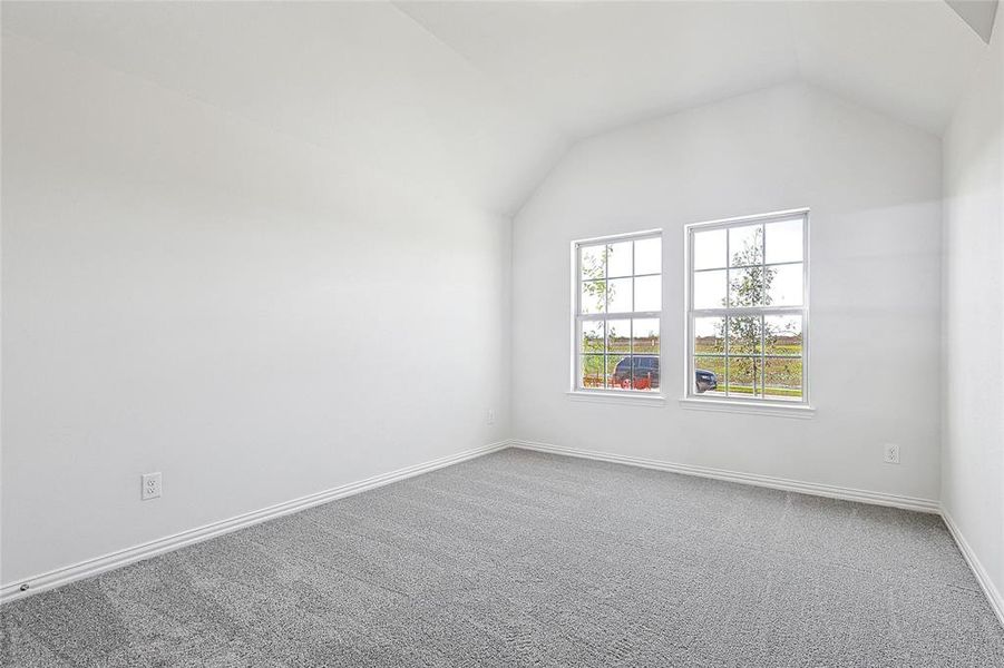 Carpeted empty room featuring vaulted ceiling