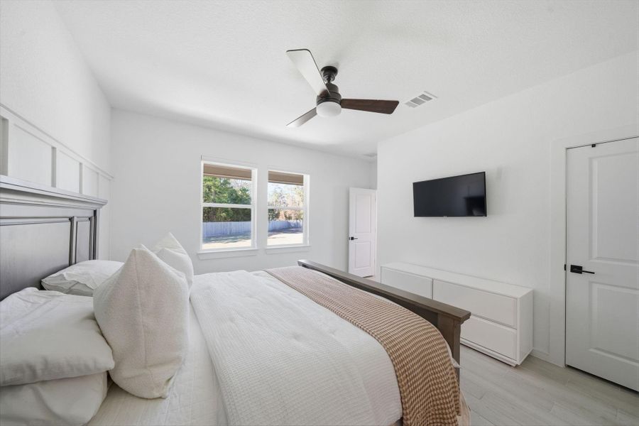 This bedroom features a modern design with  and a ceiling fan. Natural light streams in making this primary bedroom bright and inviting, perfect for relaxation.