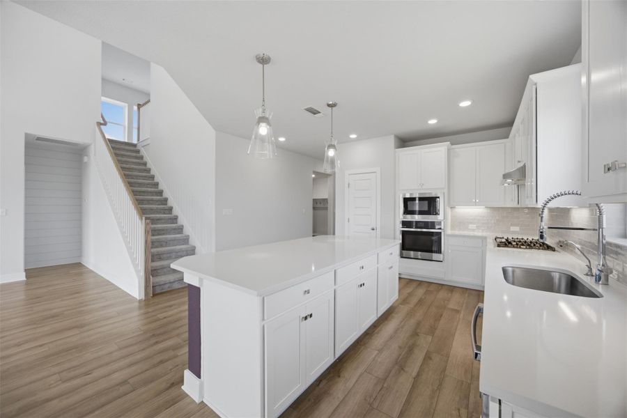 White cabinetry, sleek appliances, and wood flooring create a crisp, modern kitchen perfect for entertaining.