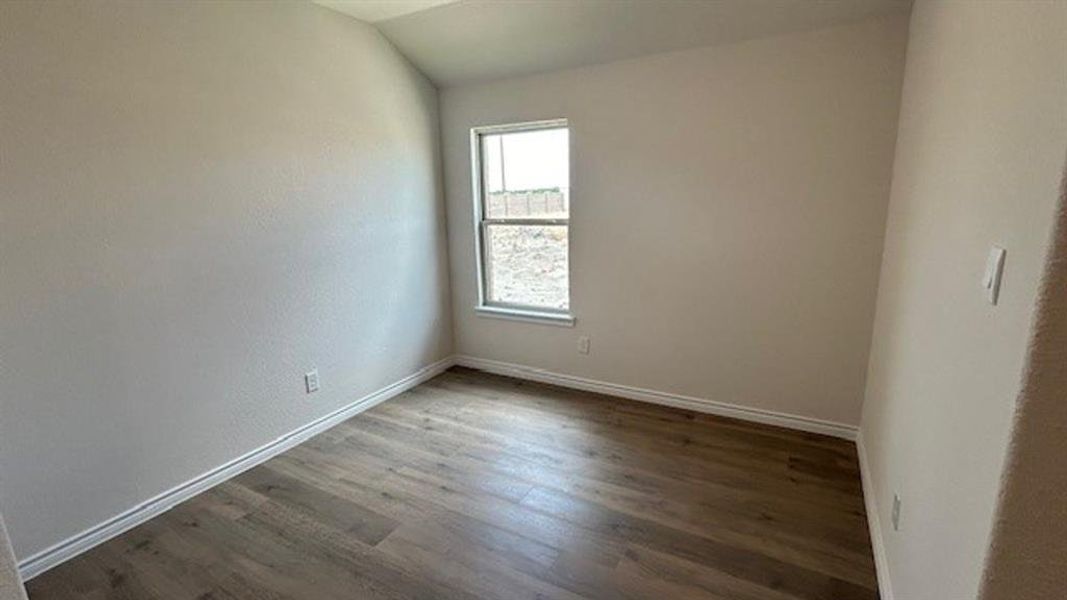 Room featuring neutral wall tones, wood-finish flooring, white trim, and a window for natural light