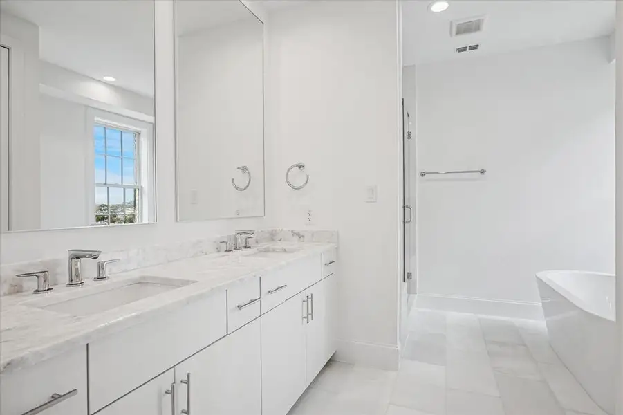 Bathroom featuring a dual vanity with undermount sinks, stone countertops, chrome fixtures, and white cabinetry