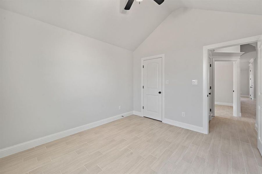 Unfurnished bedroom with wood tiled floors, ceiling fan, and high vaulted ceiling Unfurnished bedroom with wood tiled floors, ceiling fan, and high vaulted ceiling