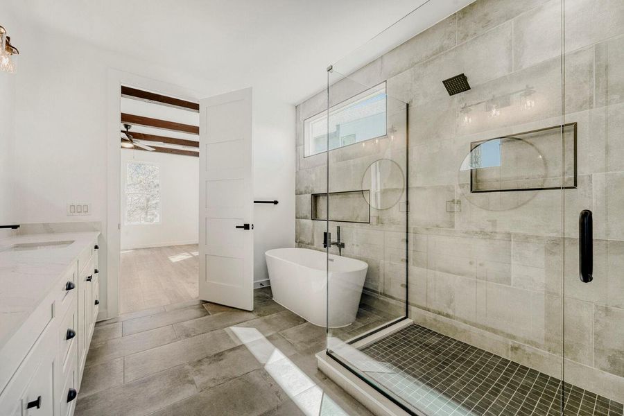 Full bathroom with a stall shower, vanity, a freestanding bath, beamed ceiling, and a ceiling fan