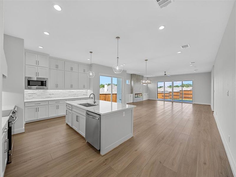 Kitchen featuring appliances with stainless steel finishes, plenty of natural light, light hardwood / wood-style flooring, and an island with sink