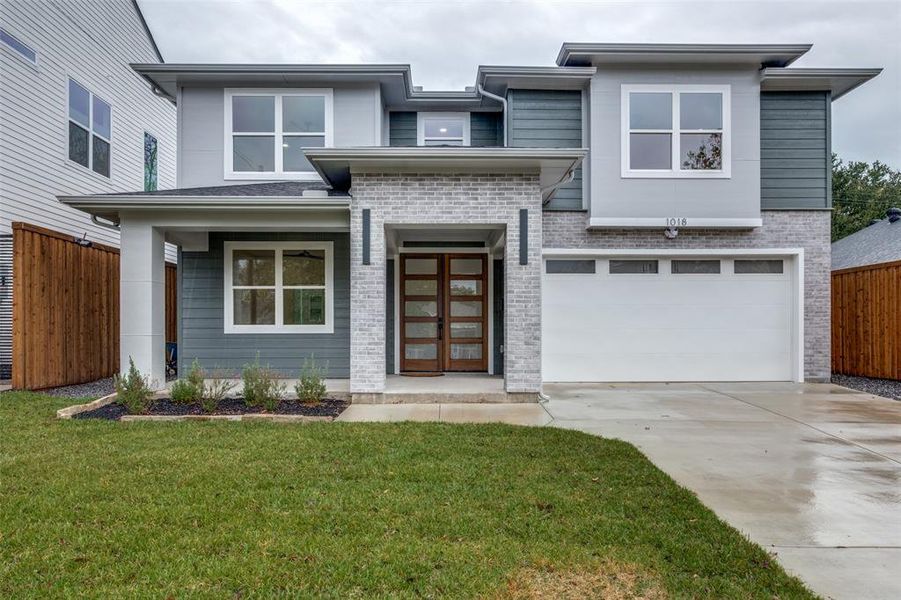 View of front facade featuring brick siding, driveway, a garage, and a porch