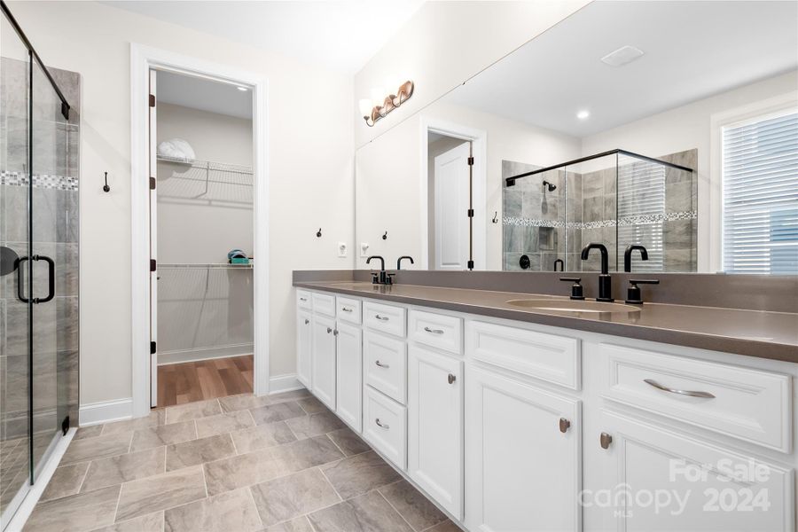 The oversized quartz counter in the Primary ensuite Bath has dual vanities with plenty of storage for all of your toiletries and has tile floors and oil-rubbed bronze fixtures.