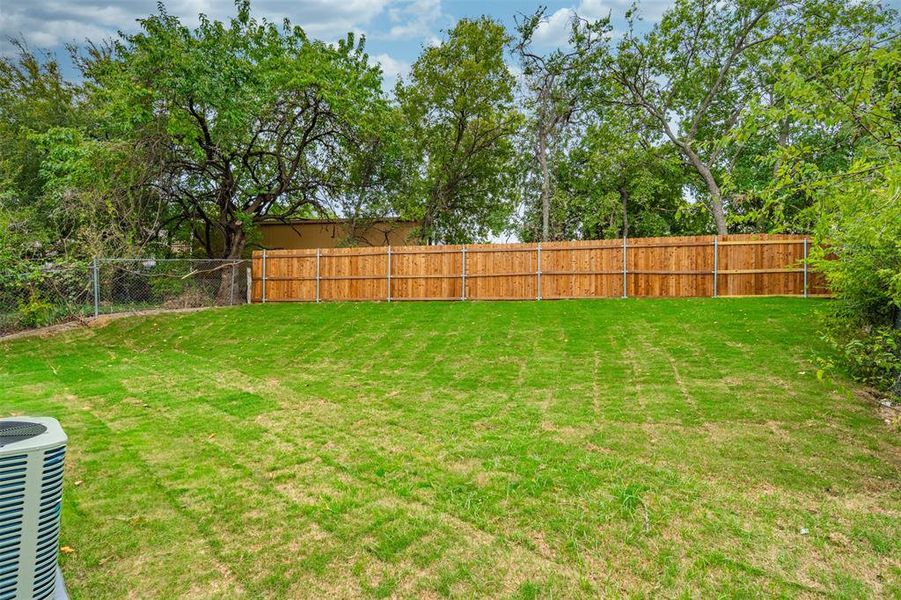 Fenced backyard with view of scattered trees