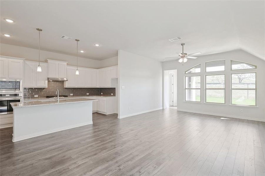 Kitchen featuring decorative backsplash, hardwood / wood-style floors, ceiling fan, white cabinetry, and stainless steel appliances