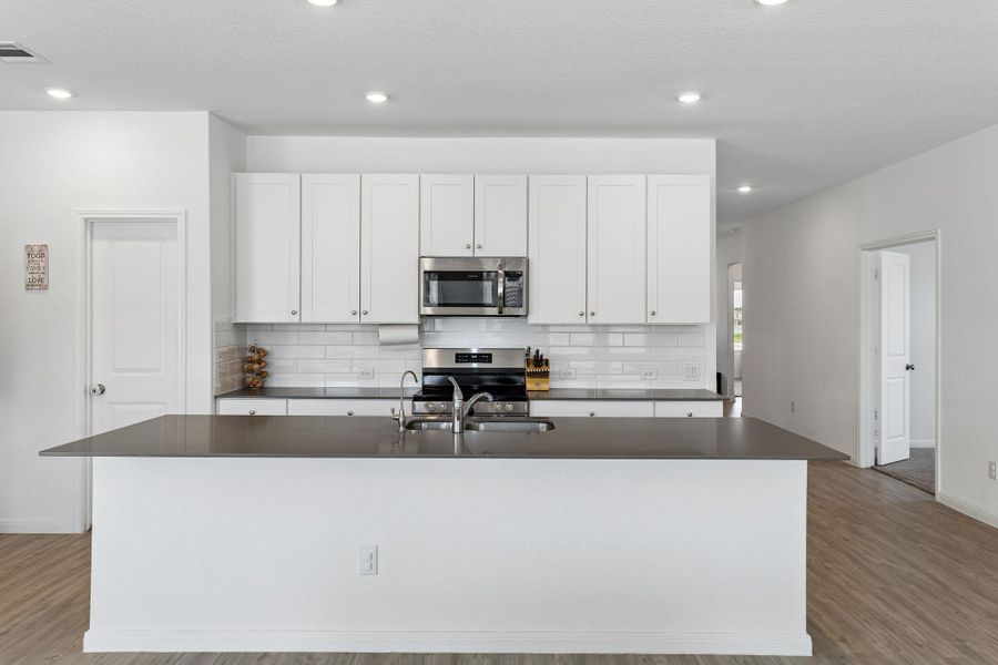 A pristine kitchen features sleek stainless steel appliances and an inviting island, perfect for culinary endeavors.