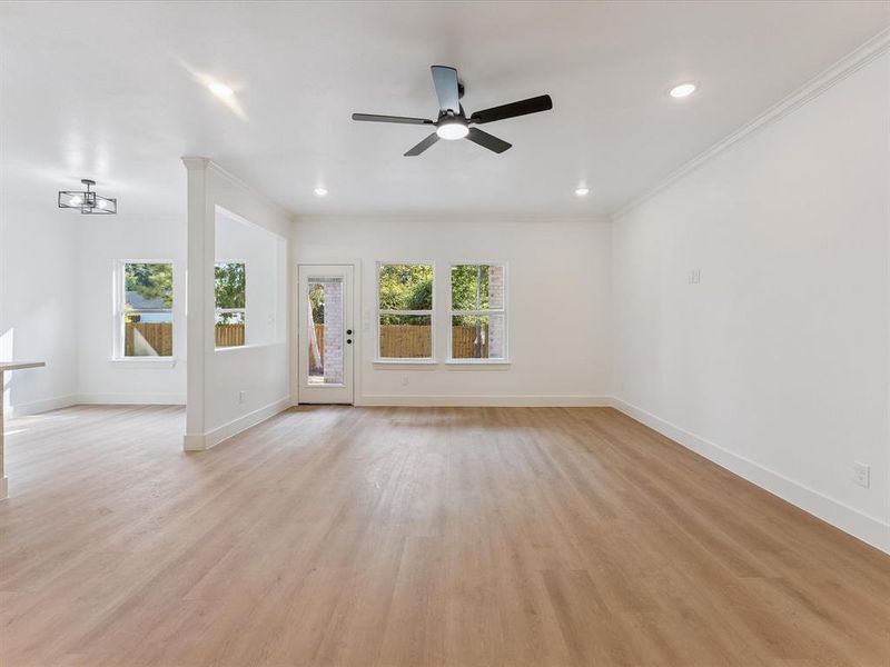 Unfurnished living room featuring crown molding, light wood-style floors, ceiling fan, and recessed lighting