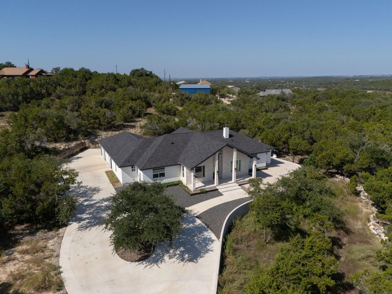 Nestled among mature trees, this contemporary home features a striking dark roof and stone facade.