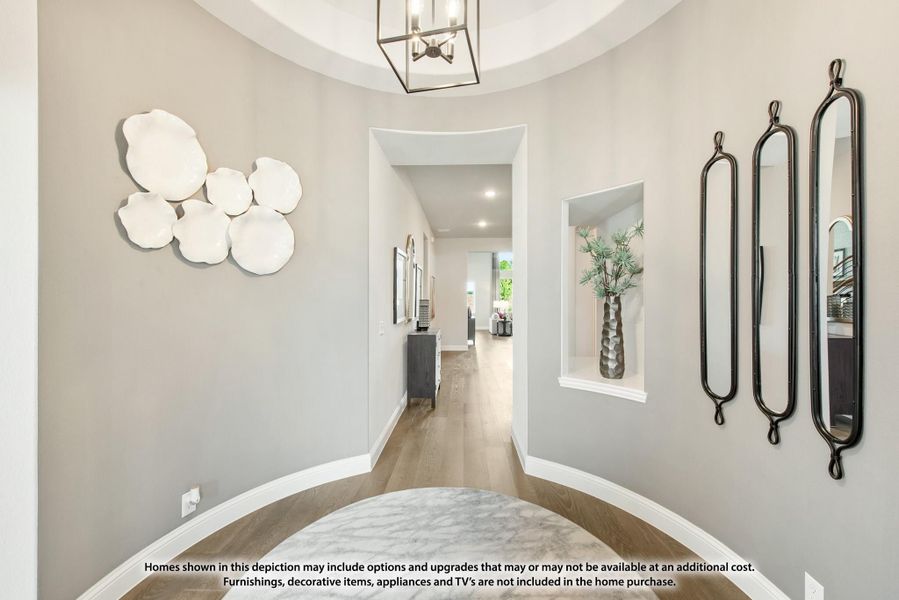 Rounded entryway foyer with hardwood floors, pendant light, wall niche, and hallway leading to main living area