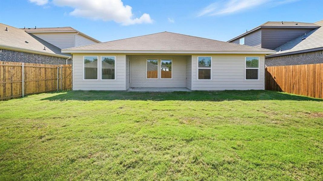 Back of property with a fenced backyard and a shingled roof