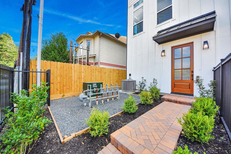 This contemporary exterior highlights clean lines and thoughtful landscaping. The driveway and gated entry provide a welcoming first impression, complementing the modern neighborhood surroundings.