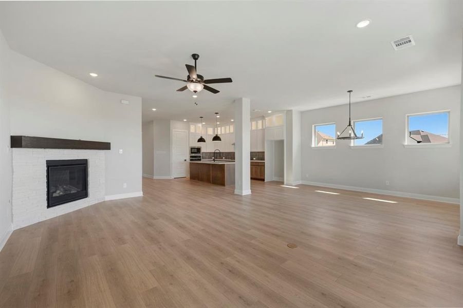 Unfurnished living room featuring a fireplace, a ceiling fan, light wood-style flooring, and recessed lighting