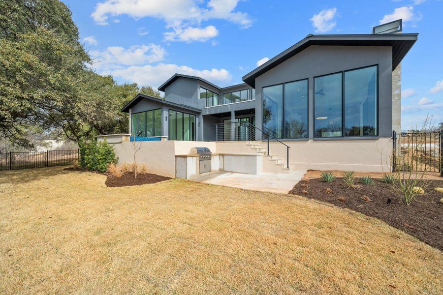 Back of house with a patio, exterior kitchen, a sunroom, and stucco siding