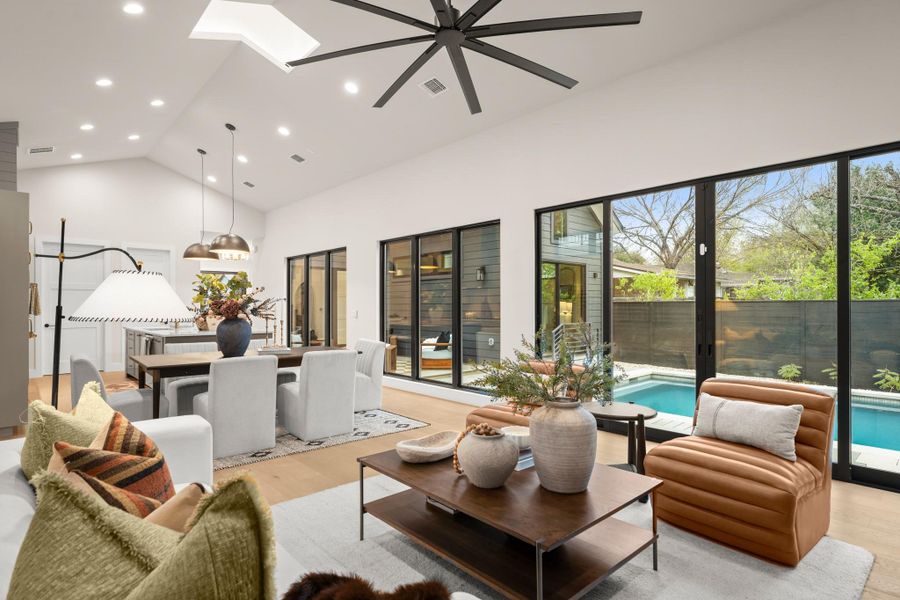 Living room featuring high vaulted ceiling, light wood finished floors, recessed lighting, and a skylight