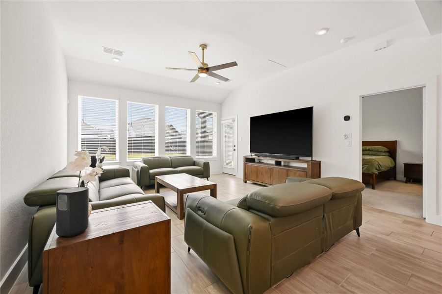 Four windows dressed in blinds overlook the backyard, bathing the living room in natural light while creating a bright, comfortable setting with relaxing outdoor views. Four windows dressed in blinds overlook the backyard, bathing the living room in natural light while creating a bright, comfortable setting with relaxing outdoor views.