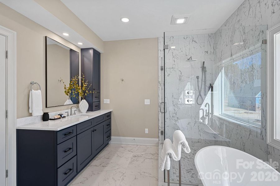 Spa-inspired Primary Bath featuring dual vanities, a soaking tub, and a beautifully appointed shower, all complemented by gorgeous tiled floors and walls.