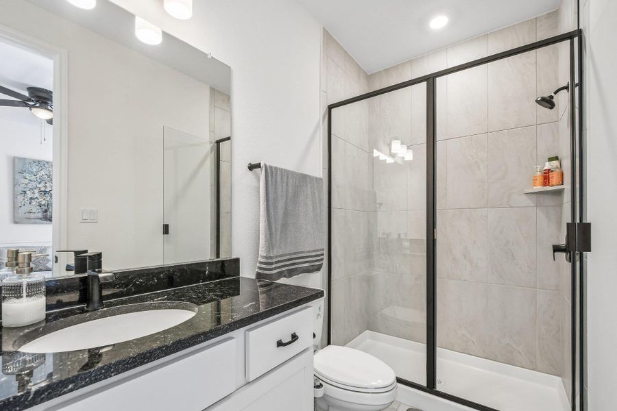 A well-appointed bathroom features a dark granite countertop vanity and a spacious glass-enclosed shower.