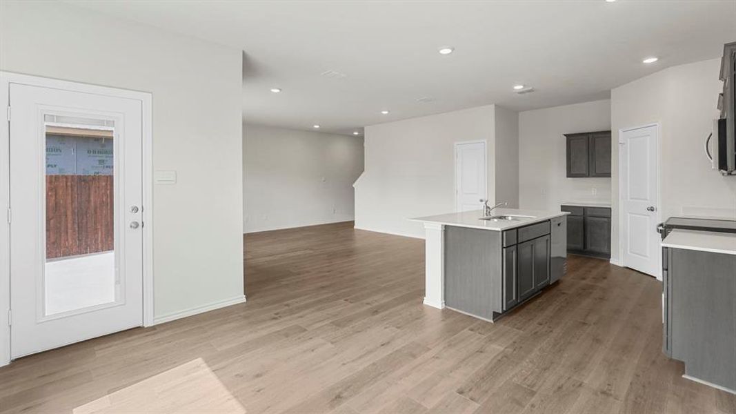 The property features an open concept kitchen and living area with light-toned flooring, white walls, and recessed lighting