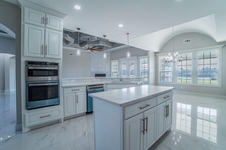Kitchen with light marble finish flooring, appliances with stainless steel finishes, white cabinets, decorative light fixtures, and recessed lighting