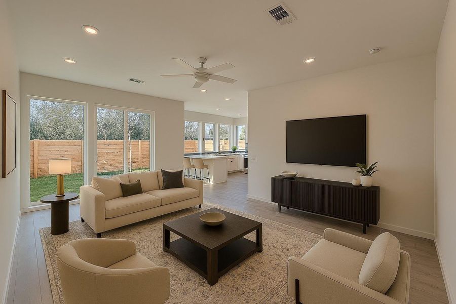 This photo showcases a modern, open-concept living area with neutral tones. It features a cozy seating arrangement, a large wall-mounted TV, and ample natural light through expansive windows. The space seamlessly connects to a bright kitchen area, creating an inviting atmosphere for family gatherings or entertaining.