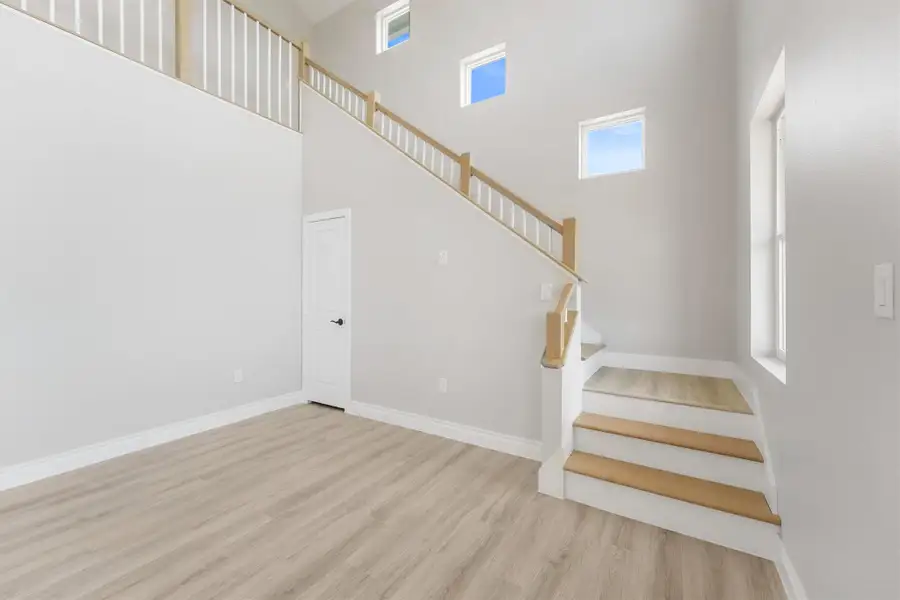 This bright, spacious room features high ceilings, modern light flooring, and a stylish staircase with wooden accents. Large windows provide ample natural light, enhancing the open feel. This bright, spacious room features high ceilings, modern light flooring, and a stylish staircase with wooden accents. Large windows provide ample natural light, enhancing the open feel.