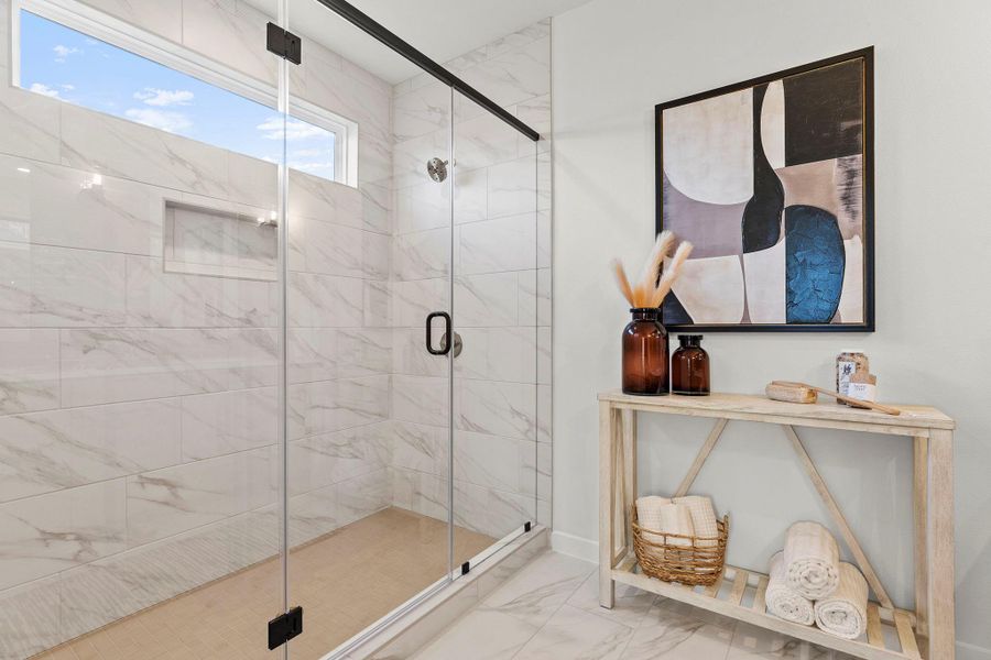 Full bath featuring a marble finish shower and light marble finish flooring