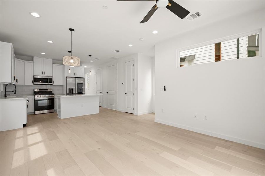 Kitchen with a kitchen island, stainless steel appliances, white cabinetry, decorative backsplash, and open floor plan