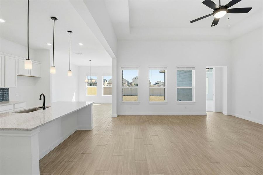 Open-concept living space featuring high vaulted ceilings, multiple windows, and wood-finish flooring