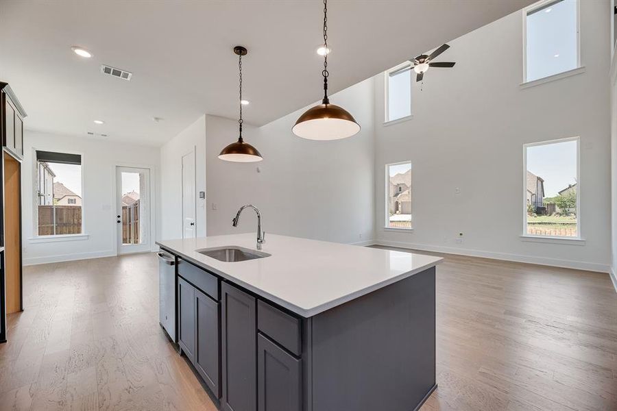 Kitchen with healthy amount of natural light, light wood finished floors, a center island with sink, a high ceiling, and recessed lighting Kitchen with healthy amount of natural light, light wood finished floors, a center island with sink, a high ceiling, and recessed lighting