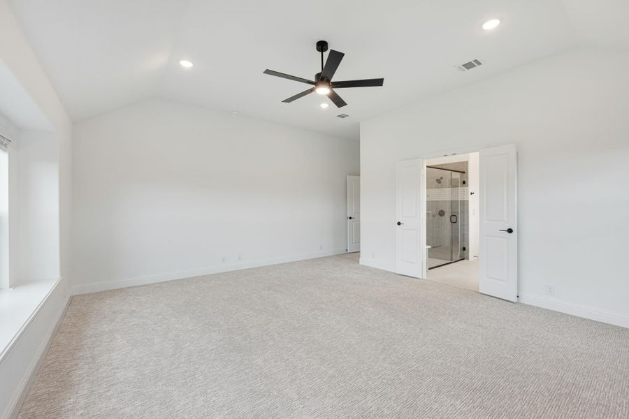 Spacious master bedroom with vaulted ceiling, ceiling fan, carpet flooring, and ensuite bathroom with glass shower. Spacious master bedroom with vaulted ceiling, ceiling fan, carpet flooring, and ensuite bathroom with glass shower.