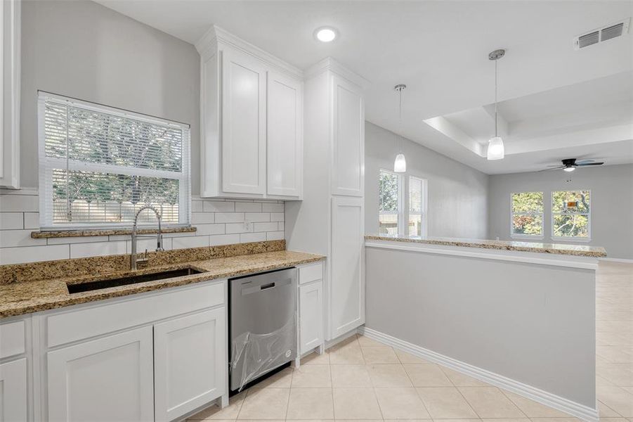 Kitchen with ceiling fan, sink, dishwasher, white cabinetry, and hanging light fixtures