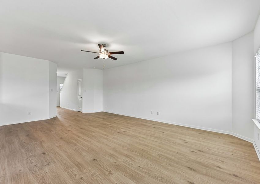 Family room featuring a ceiling fan, wood-look vinyl flooring, and natural light.