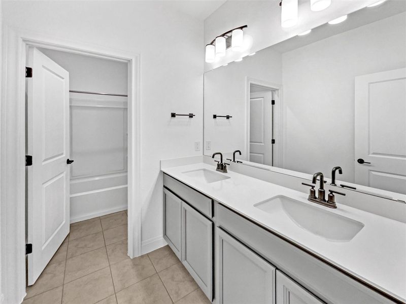 Full bathroom featuring tile patterned floors, double vanity, shower / bath combination, and a sink