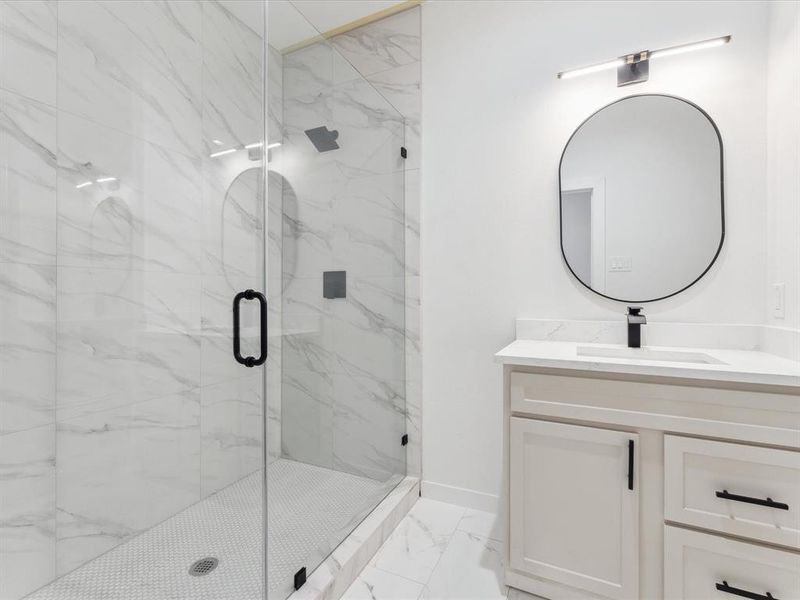 Bathroom with marble finish floor, a marble finish shower, and vanity