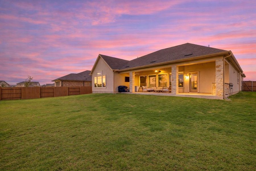 The property features an extensive green lawn with a wooden fence