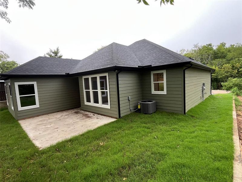 Rear view of property with a lawn, a patio, and a shingled roof Rear view of property with a lawn, a patio, and a shingled roof