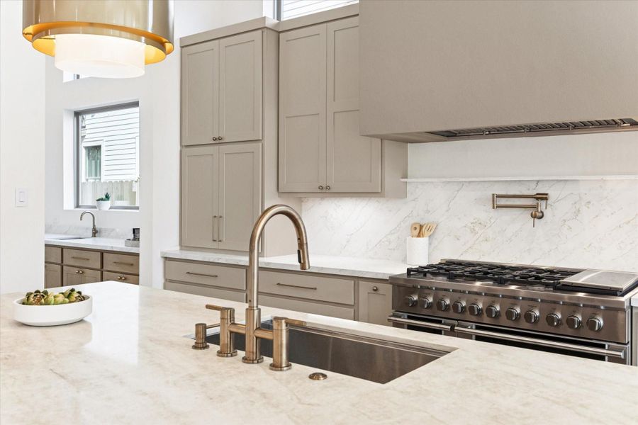 This magazine-worthy kitchen features a Delta faucet, pot filler, and two striking 20” pendants illuminating the island.