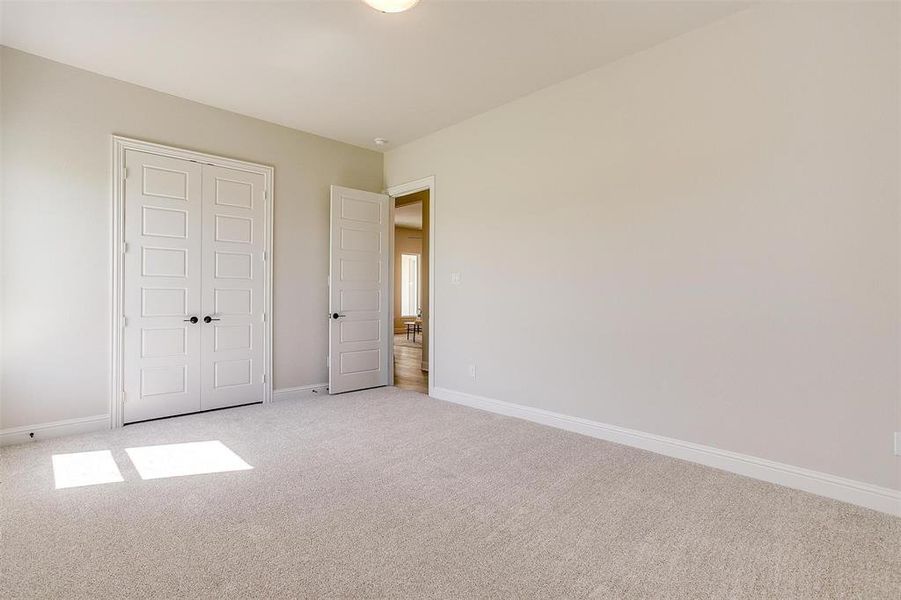 Unfurnished bedroom featuring light carpet and a closet