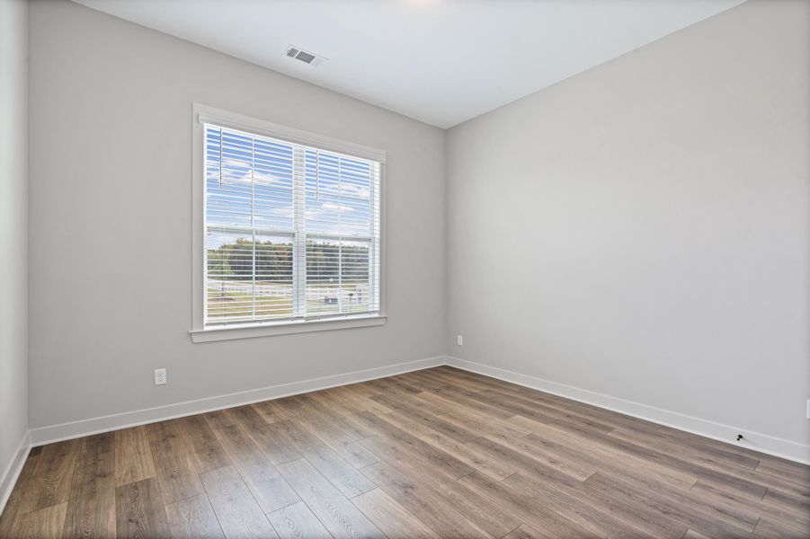 Wood-finish flooring, neutral wall tones, large window with blinds, and white trim