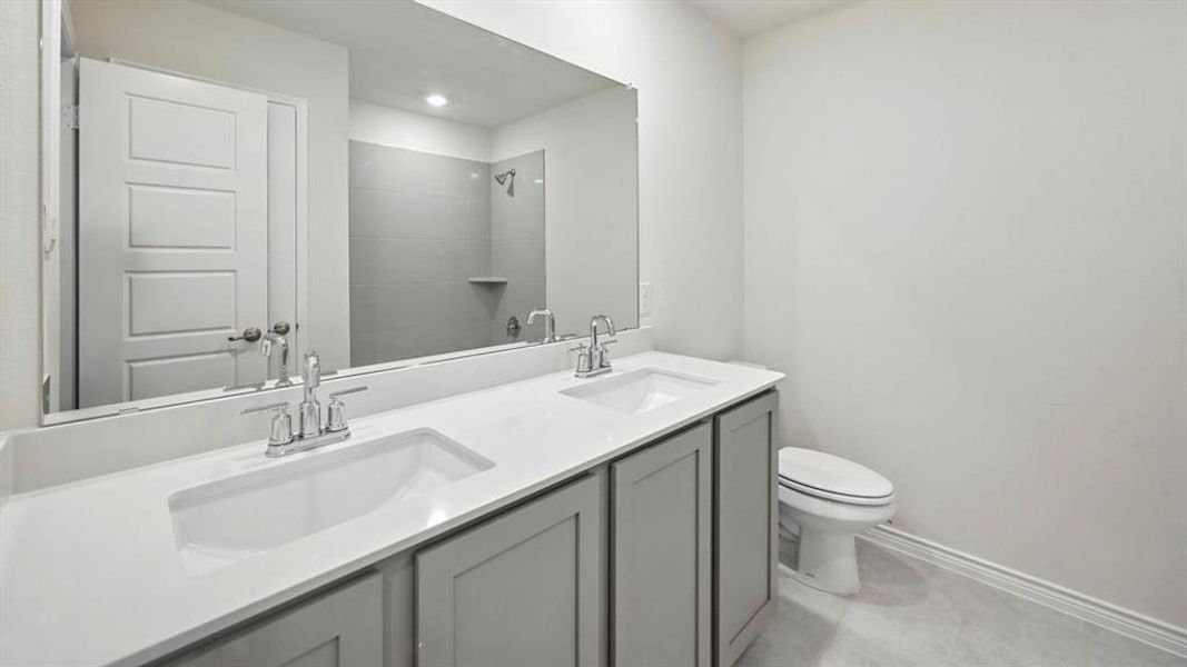 Full bathroom with double vanity, tiled shower, and light tile patterned floors